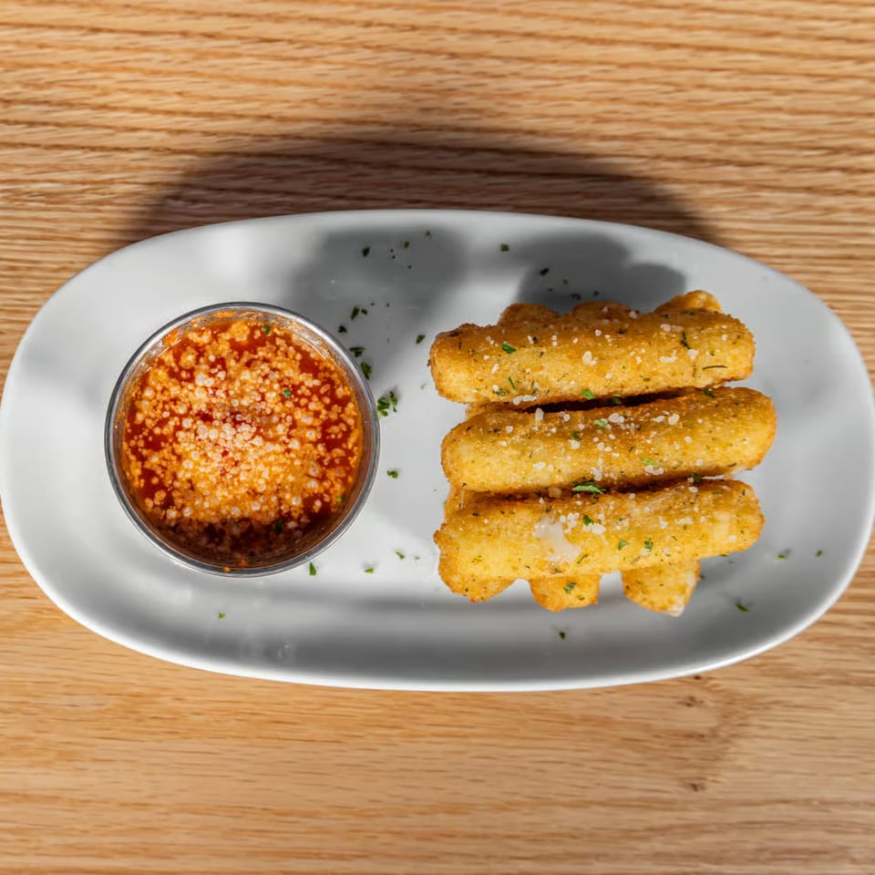 Golden-brown mozzarella sticks with marinara sauce and parmesan cheese on a white plate.